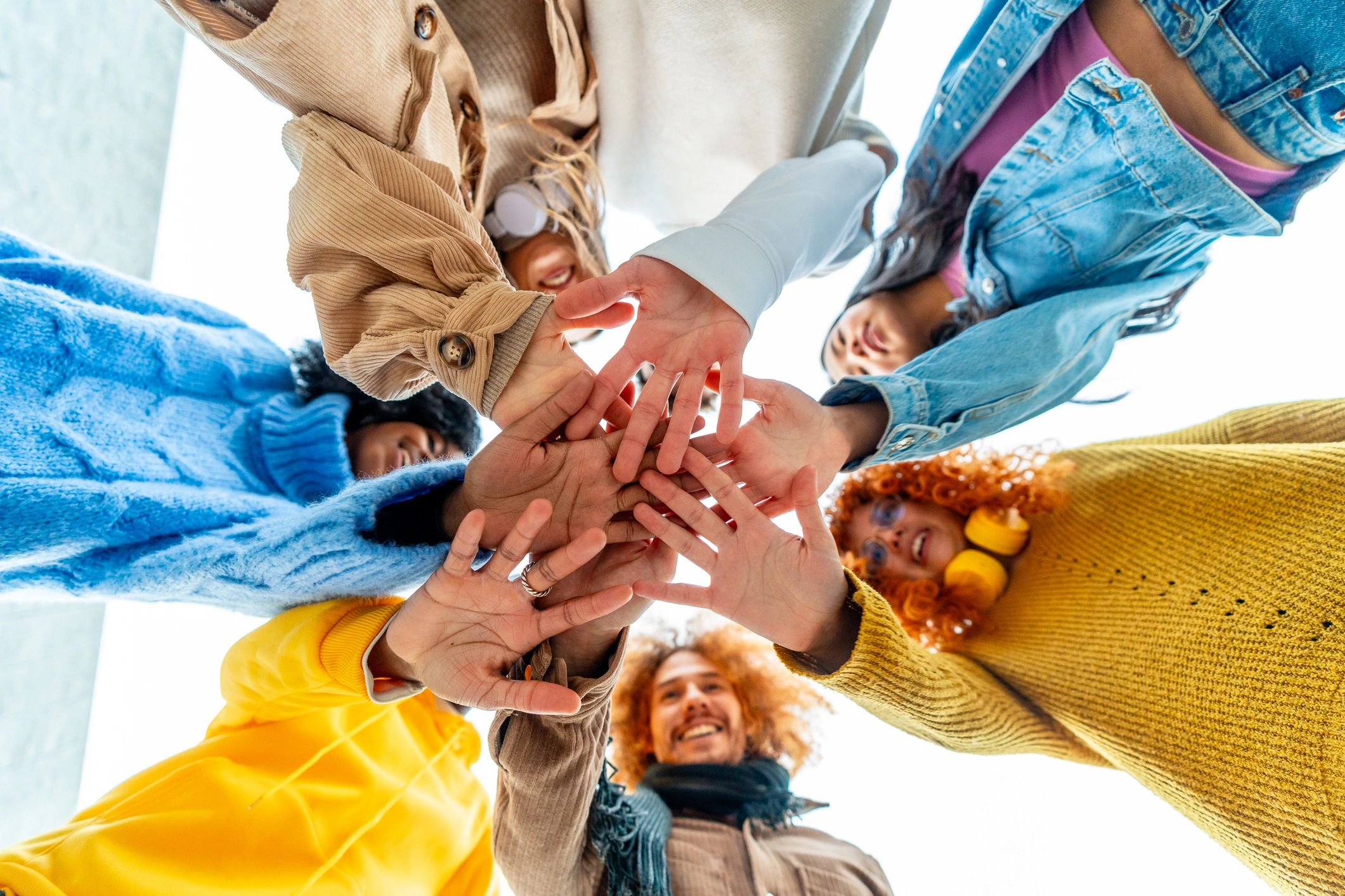 Group of diverse young people join hands in circle